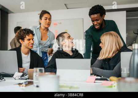 Happy business professionals planning ideas while discussing with each other in tech startup office Stock Photo
