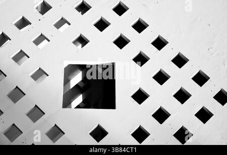 abstract composition formed by a white wall with several small windows around a large window Stock Photo