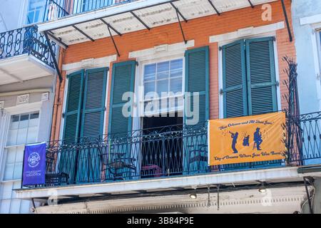 New Orleans, LA, USA - April 13, 2025: Second story apartment of historic French Quarter building displaying flags for WWOZ Radio Station and New Orleans Jazz during the French Quarter Festival Stock Photo