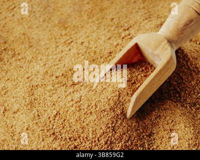 Background texture of raw organic coconut sugar from crystallized sap of cut flower buds coconut palm. Brown coconut palm sugar and wooden scoop. Alte Stock Photo
