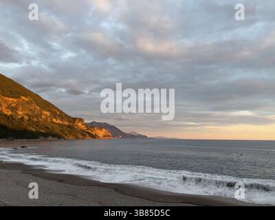 Mountain range in the rays of the setting sun on the seashore. Stock Photo