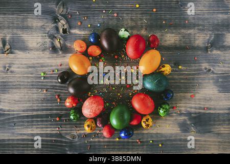 A ring of Easter eggs on a wooden background. A circle of colorful eggs and decorative sugar powder. Easter backgrounds. Stock Photo