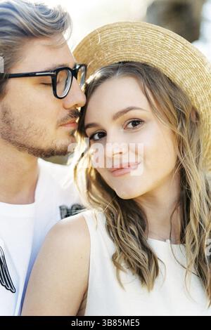 Man in glasses touches his lips the forehead of a smiling woman. Portrait. Stock Photo