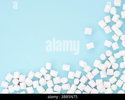 Marshmallows on blue background with copyspace. Flat lay or top view. Background or texture of colorful mini marshmallows Stock Photo