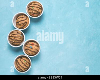 Safe-to-eat raw monster cookie dough in small portion bowl on blue background. Ideas and recipes for kids and toddlers meal. Top view or flat-lay. Cop Stock Photo