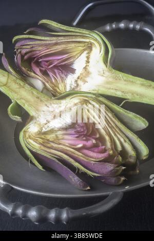 An artichoke, halved in a pewter bowl Stock Photo