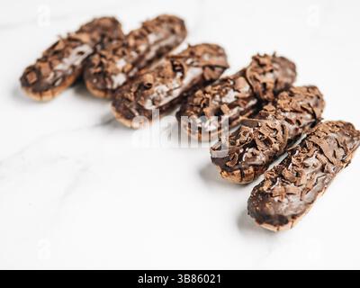 Set of homemade eclairs with chocolate on marble background. Close up view of delicious healthy profitroles with chocolate glaze. Copy space for text Stock Photo