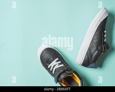 Pair of new kids or adult sneakers on blue background, top view. Flat lay gray and yellow or mustard color sneakers shoes on colorful bright blue back Stock Photo