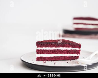 Piece of red velvet cake with perfect texture in matte plate on white marble tabletop. Slice of delicious homemade red velvet cake with raspberry and Stock Photo