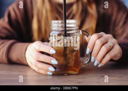 Long island iced tea in glass. Woman holding cold drink. Fresh beverage with ice cubes. Summer refreshment. Refreshing cold tea. Chilling with drink. Stock Photo