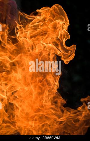 Close-up of bright orange flames rising against a dark background – abstract image symbolising fire, energy, destruction, or transformation Stock Photo