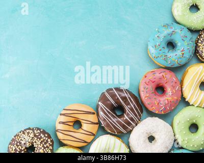 Top view of assorted donuts on blue concrete background with copy space. Colorful donuts background. Various glazed doughnuts with sprinkles Stock Photo