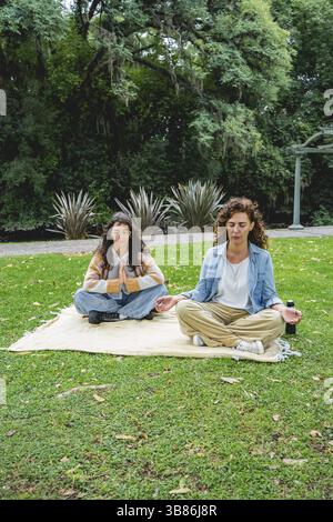 Vertical shot of two women practicing mindfulness and meditation on grass Stock Photo