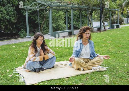 Two women practicing mindfulness and meditation on grass Stock Photo