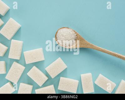 Background of sugar cubes and sugar in spoon. White sugar on blue background. Sugar with copy space. Top view or flat lay Stock Photo