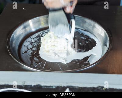 Making rolled ice cream. Man hands making kiwi and banana Thay style natural ice cream Stock Photo