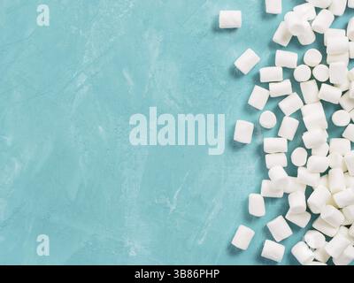 Marshmallows on blue background with copyspace. Flat lay or top view. Background or texture of colorful mini marshmallows. Winter food background conc Stock Photo