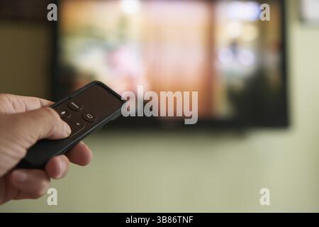Multimedia streaming concept. Hand holding remote control. TV screen with lot of pictures Stock Photo