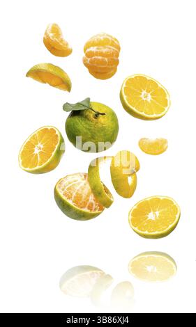 Fresh ripe green mandarine with leaf falling in air. Cut, peeled, slices and whole green tangerine isolated on white background with clipping path. Fo Stock Photo