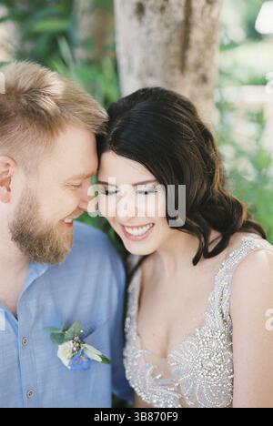 Bride and groom laugh, touching their foreheads to each other. Portrait. Stock Photo