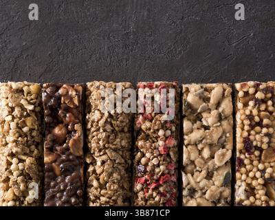 Granola bar with copy space. Set of different granola bars on black background. Shallow DOF. Top view or flat lay Stock Photo