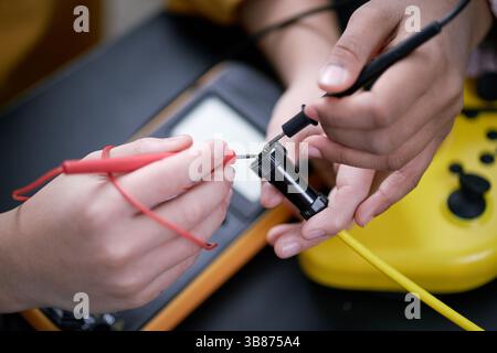 Close-up of hands connecting electrical components using multimeter probes for testing voltage and current in circuit. Black and red leads in focus wh Stock Photo