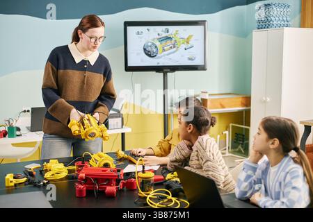 Educator demonstrating engineering concepts to children in a vibrant classroom. Students engaging with tools and models, fostering hands-on learning a Stock Photo