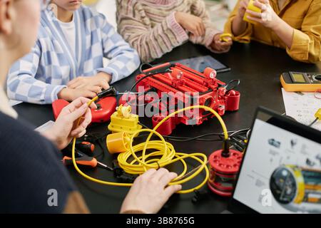 Group of children engaged in building a robotic project with various components and tools Science project involving teamwork and learning technology Stock Photo