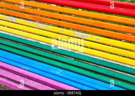 Colorful Rainbow Bench in a Vibrant Park Surrounded by Trees and Greenery Stock Photo