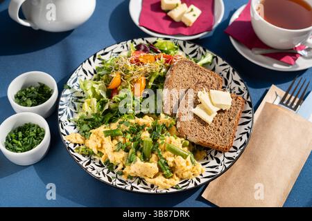 Scrambled eggs with vegetables, asparagus, toast, chives, seed sprouts and greens served on a beautifully decorated plate, a breakfast set Stock Photo