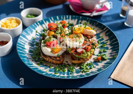 Soft boiled eggs served with toast and pesto with avocado and red onion, served on a beautiful blue and white plate. A breakfast set Stock Photo