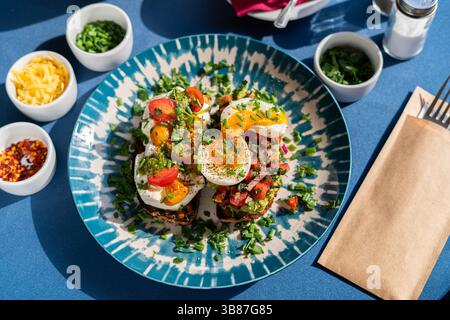 Soft boiled eggs served with toast and pesto with avocado and red onion, served on a beautiful blue and white plate. A breakfast set Stock Photo