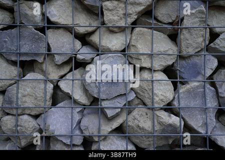 grey stone background. retaining wall of caged rocks in metal cage. gabions Stock Photo