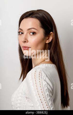 Beautiful woman in white knitted sweater posing indoors Stock Photo