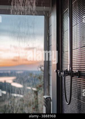 Bathing room interior with panoramic window. Splashes and drops of water from shower in bathroom with panoramic window in summer nature background at Stock Photo