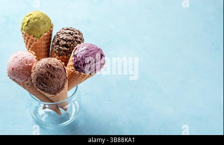 Various ice cream scoops in cones with copy space. Colorful ice cream in cones chocolate, strawberry, blueberry, pistachio or matcha, biscuits chocola Stock Photo