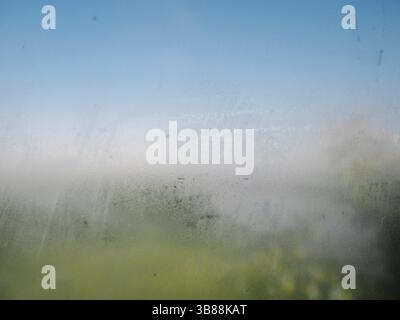 Condensation on clear glass window in panoramic bathroom or shower room. Water drops and condensed stem on glass at summer sunny day background. Abstr Stock Photo