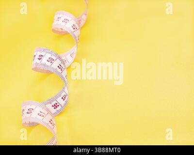 Red and white measuring tape on yellow background Stock Photo