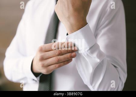 Man in a tie buttons up the sleeves of a white shirt. Close-up. Stock Photo