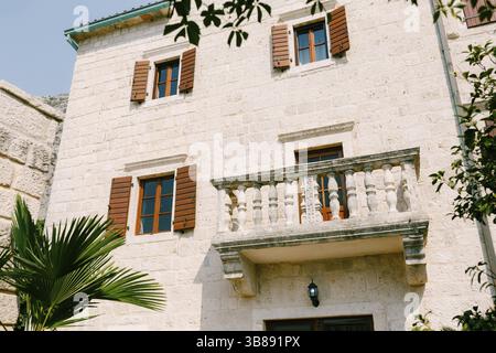 Beautiful antique balcony in a light stone building with wooden shutters. Stock Photo