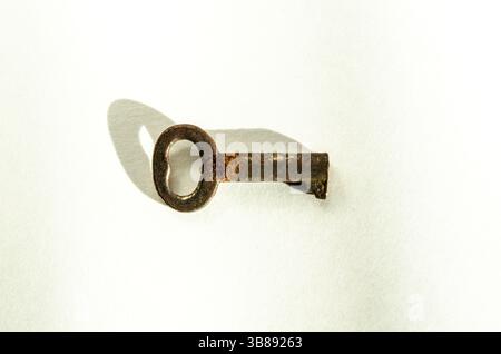 Small,Simple Antique Brass Skeleton Key on White Background, shown at a side view macro closeup Stock Photo