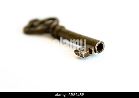 Antique Brass Skeleton Key end on White Background, shown at an angled  view macro closeup Stock Photo