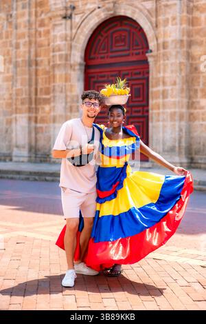 Colombia, Cartagena - April 16, 2025: Happy young Latin man and cheerful Afro-Latina Palenquera woman in colorful dress pose together in Cartagena, Stock Photo