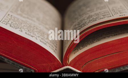 Close-up of open book with glossy pages and striking red edges Stock Photo