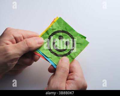A man holding a stack of colorful paper notes with happy faces on them. Close up. Stock Photo
