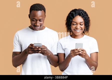 Excited young man and woman playing together on smartphones Stock Photo
