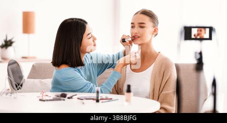 Asian Woman Doing Makeup For Her Beautiful Model Stock Photo