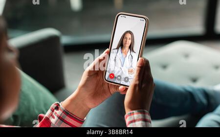 Telemedicine. Unrecognizable Woman Using Smartphone, Making Video Conference With Her Therapist Doctor Stock Photo