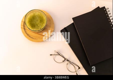 Close-up of a stack of books and a freshly made matcha latte in a ceramic cup, creating a warm and calming reading atmosphere. Stock Photo