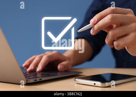 Approved. Man using laptop and touching virtual screen with check mark at table, closeup Stock Photo